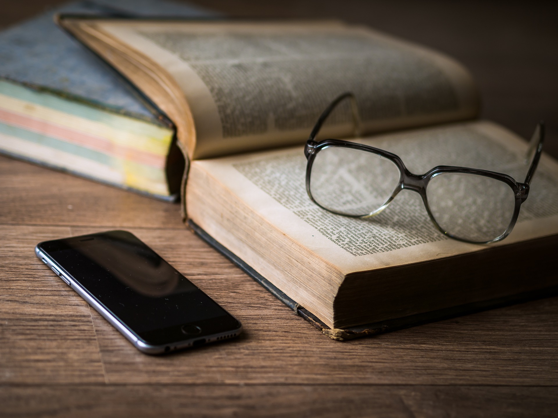 Smartphone with glasses and a book illustrating the launch of a Stack Overflow extension for the GitHub Copilot AI assistant for developers, enabling users to access the vast knowledge platform to find solutions for software development problems.